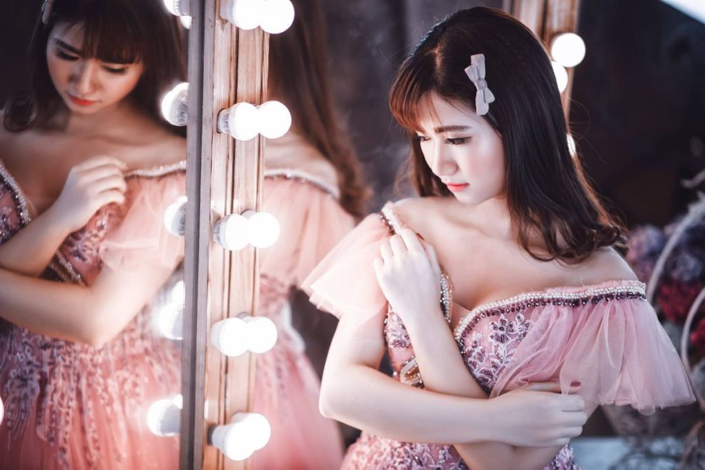 Woman in a pink dress wearing coloured contact lenses during a photoshoot